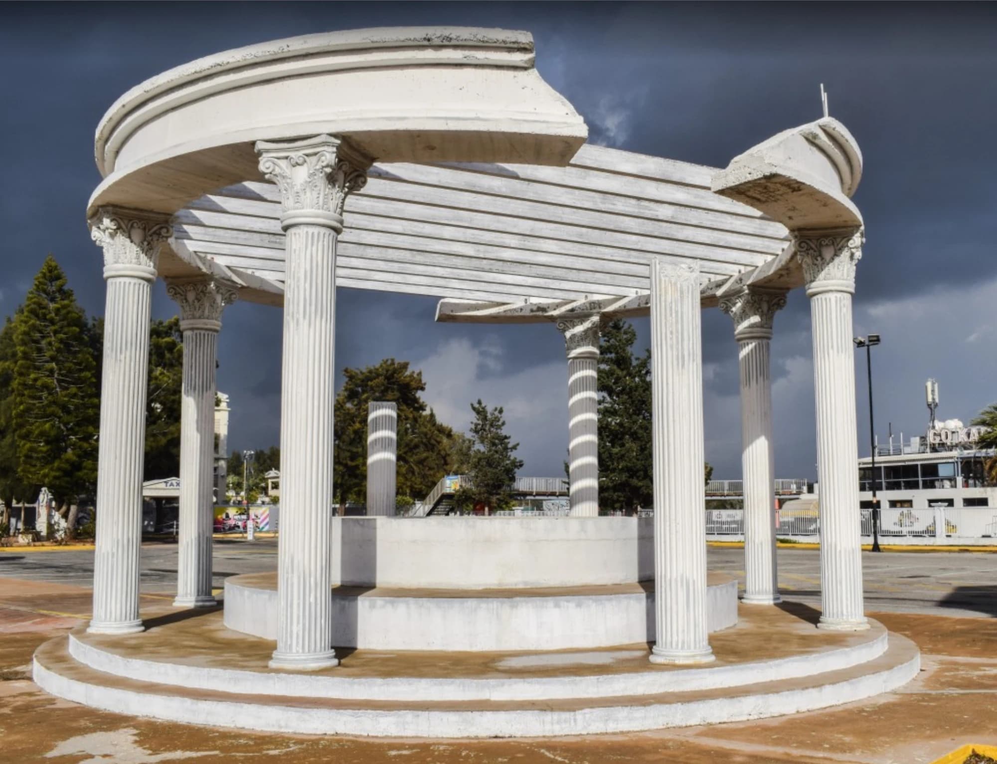 Outdoor circular colonnade installation with white fluted columns, ornate Corinthian capitals, and curved entablature beams.