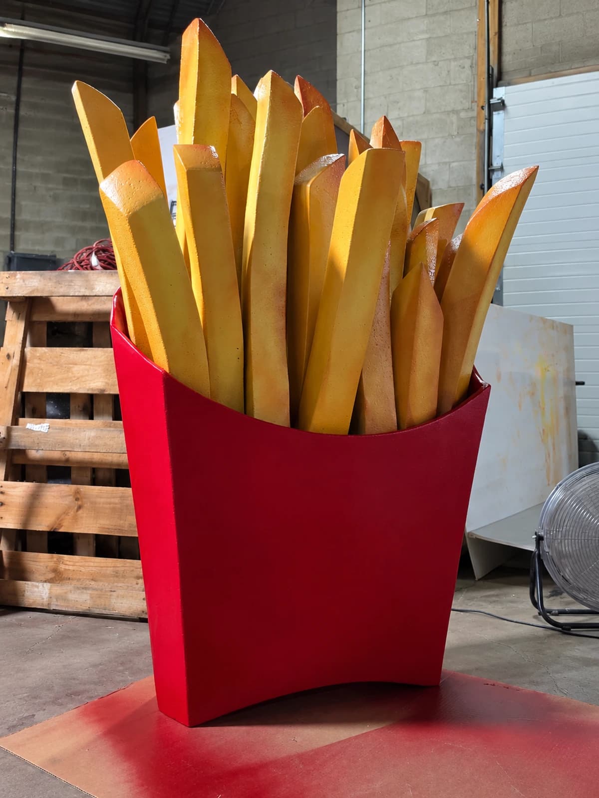 Oversized French fry trade show prop finished in red and golden yellow paint.