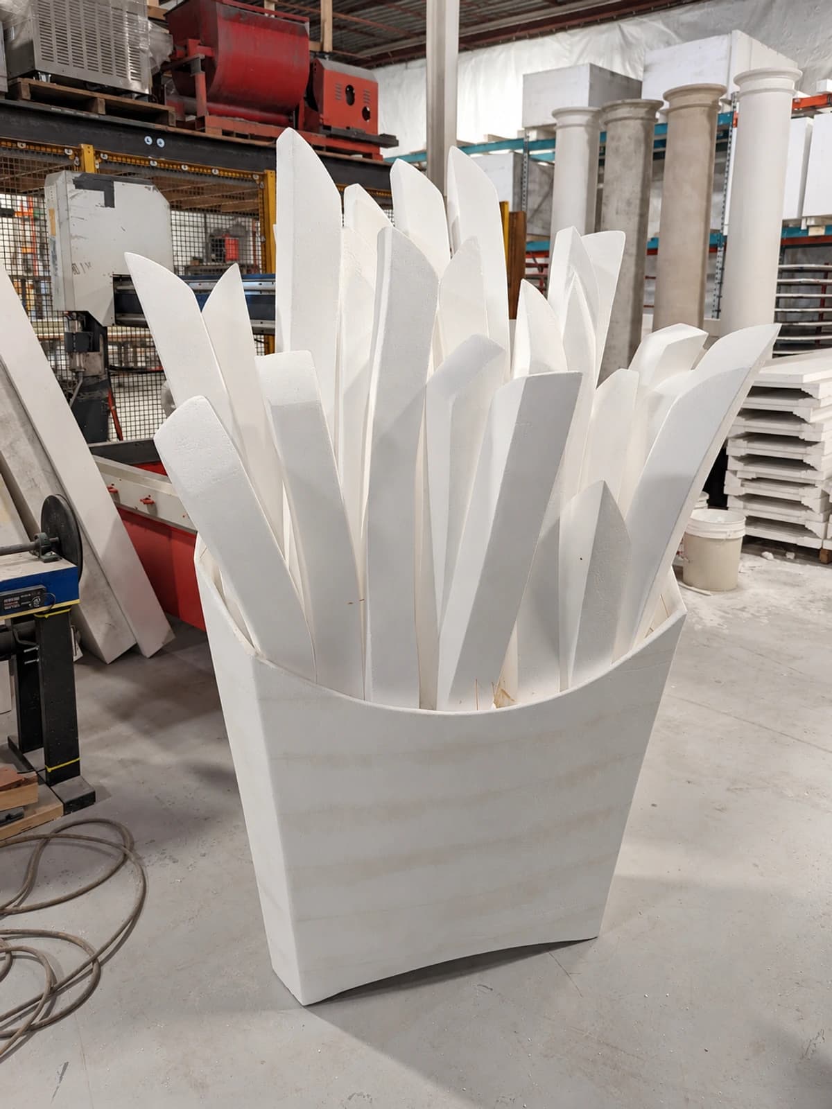 Uncoated white foam fries arranged in an oversized foam carton in the workshop.