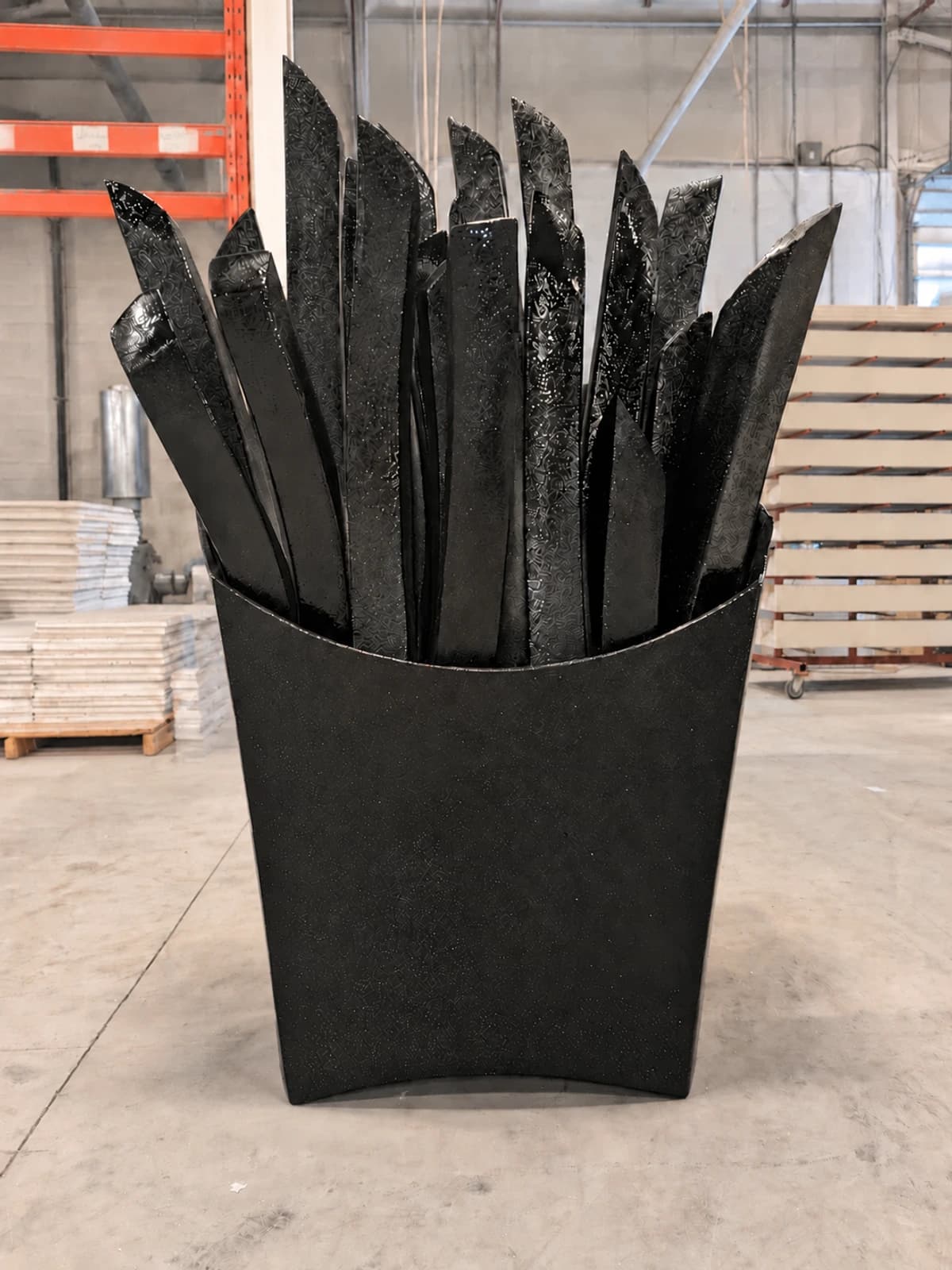 Oversized French fry prop sprayed in a protective black polyurea shell in the workshop prior to final painting.