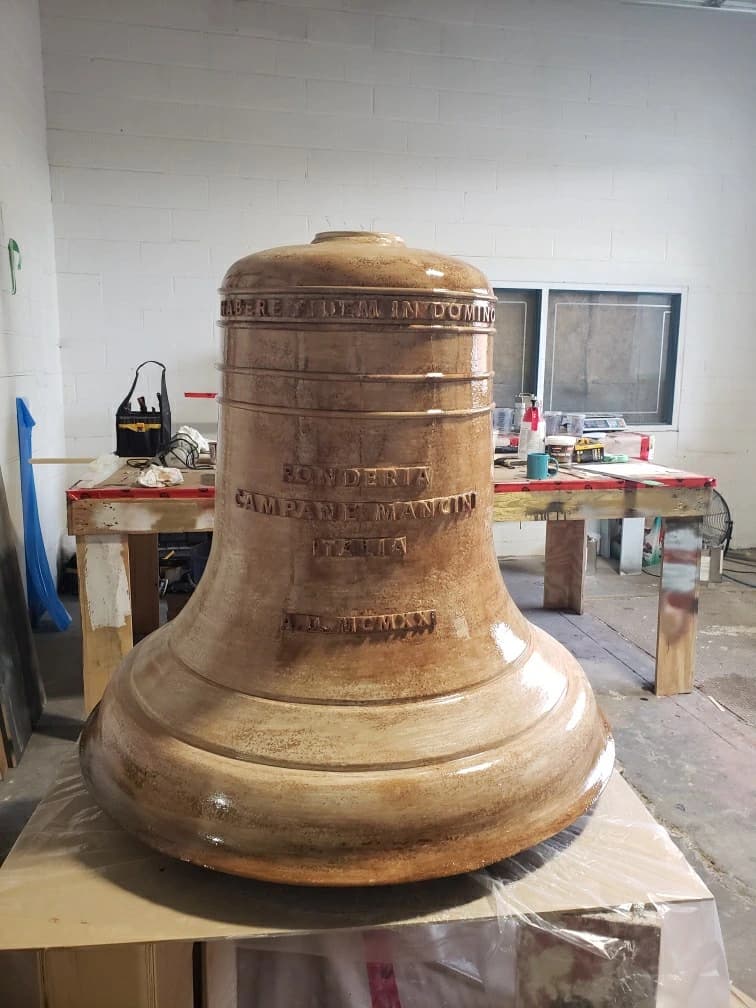 Large film bell prop with an aged metallic finish and raised lettering.